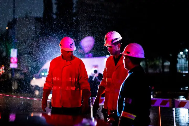 Technicians of Edenor electricity company stand under the rain as they work to fix a generator during a blackout in Buenos Ai